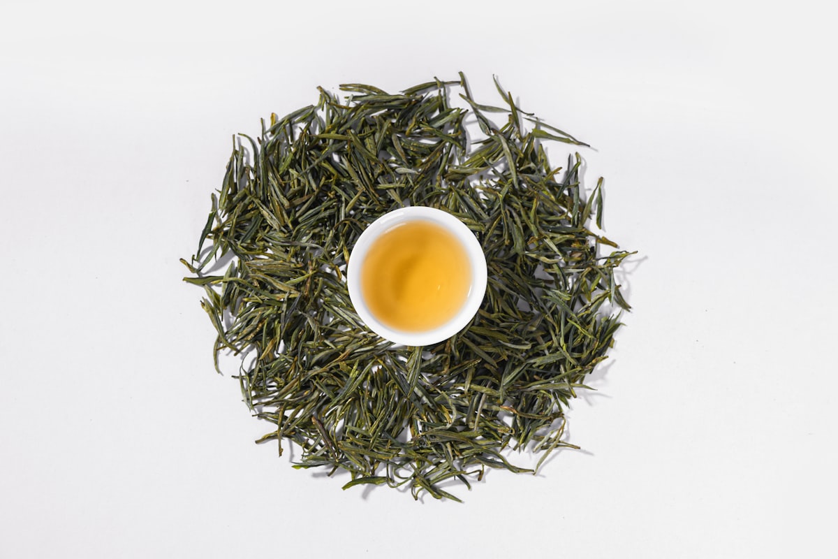 緑茶の茶葉に囲まれた、淹れたての緑茶が入った小さな器
